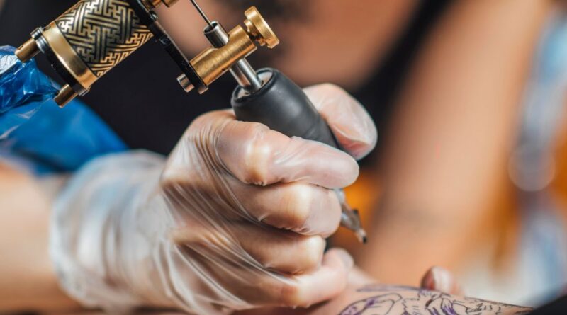 Nghệ sĩ xăm đeo găng tay chuẩn bị kim xăm fine line