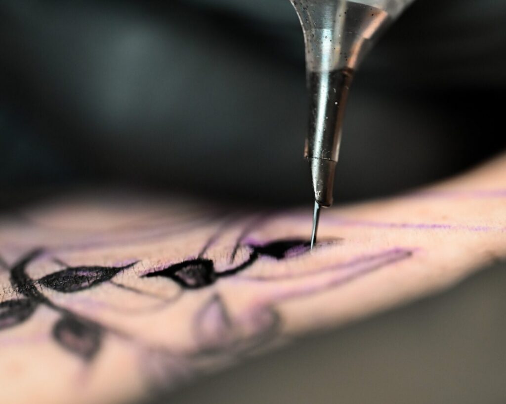 Close-up of a fine line tattoo needle depositing ink into the skin for detailed cover-up work.