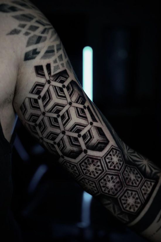 Client and artist reviewing geometric tattoo design on a tablet during consultation.