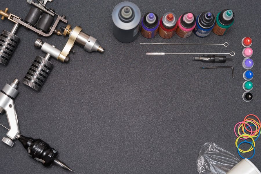 A tattoo artist wearing a surgical mask and disposable gloves while tattooing.