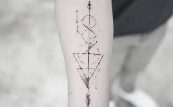 A tattoo artist sketching a geometric mandala design on paper.
