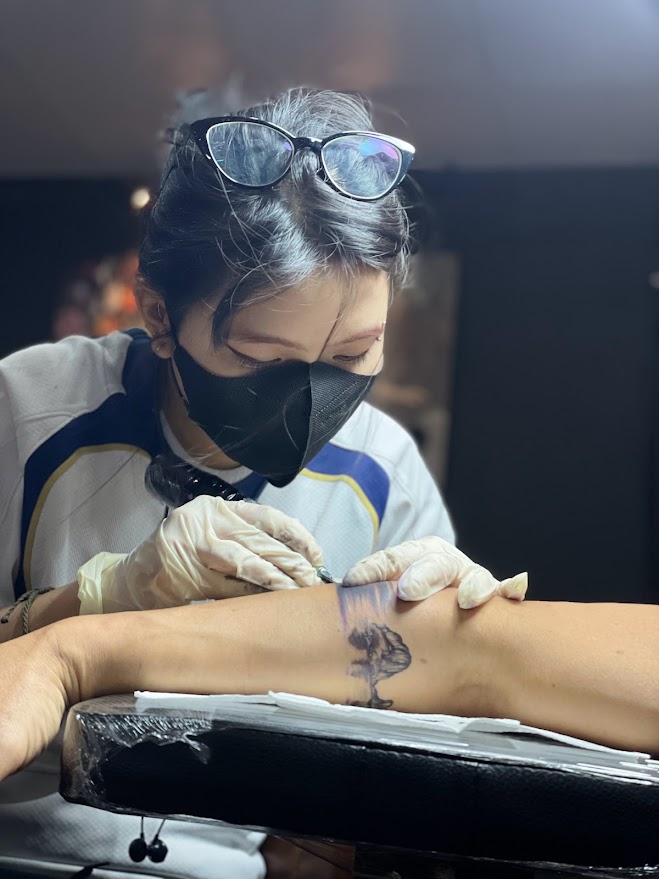 Nghệ sĩ phác thảo thiết kế xăm tùy chỉnh trong buổi tư vấn.
