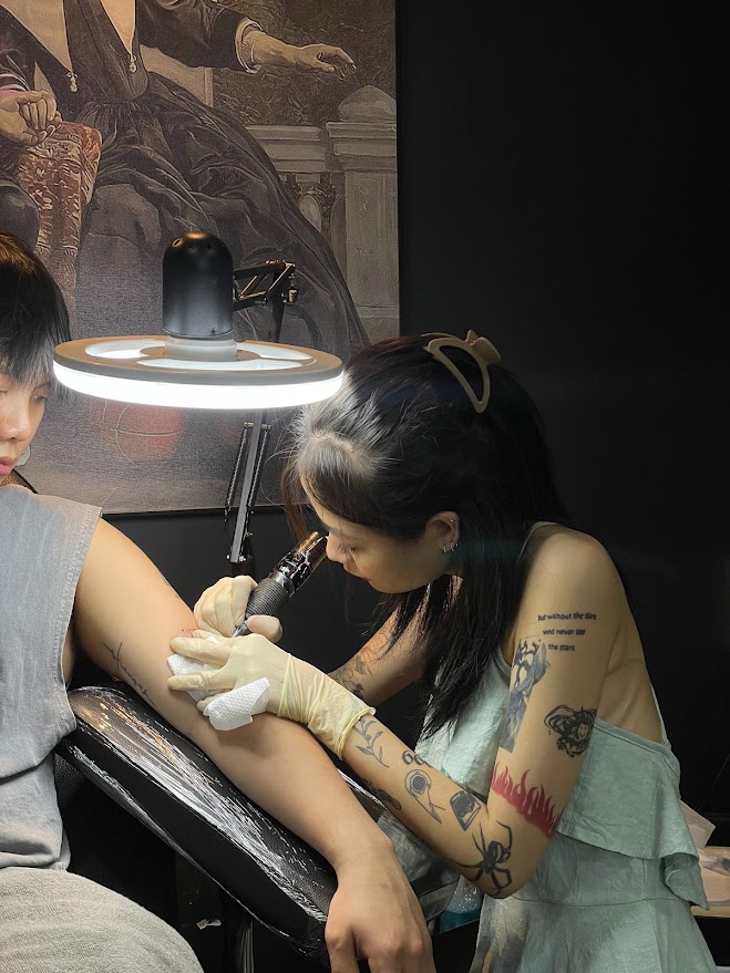 A tattoo artist showing a portfolio book with various designs.