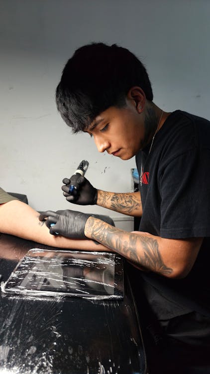 A tattoo artist carefully placing a stencil on a client's arm before starting the tattoo.