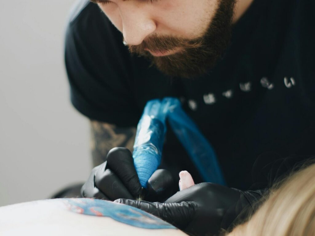 A client discussing watercolor design ideas with a tattoo artist in a studio.