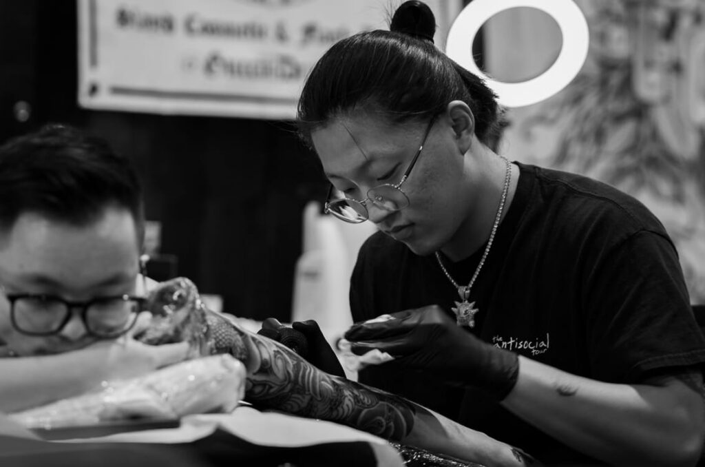 Thợ xăm cẩn thận đặt giấy nến lên cánh tay khách hàng cho thiết kế nhỏ.