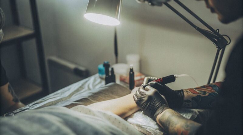 A tattoo artist applies a thin layer of moisturizer to a minimal tattoo.