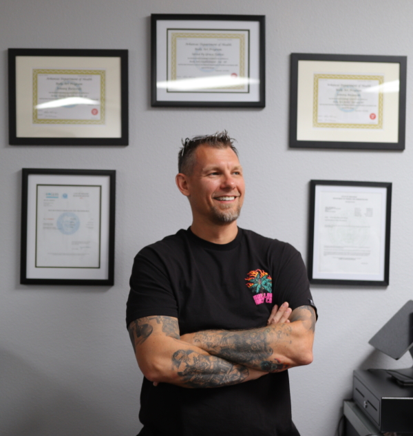 A framed certificate of a tattoo artist hanging on a studio wall.