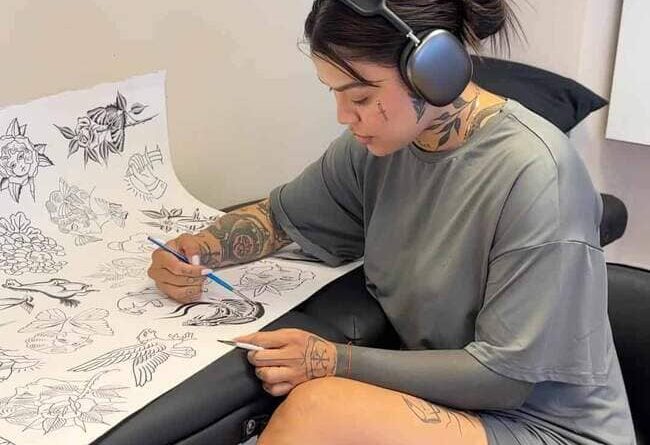 Tattoo artist sketching a minimal tattoo design on paper