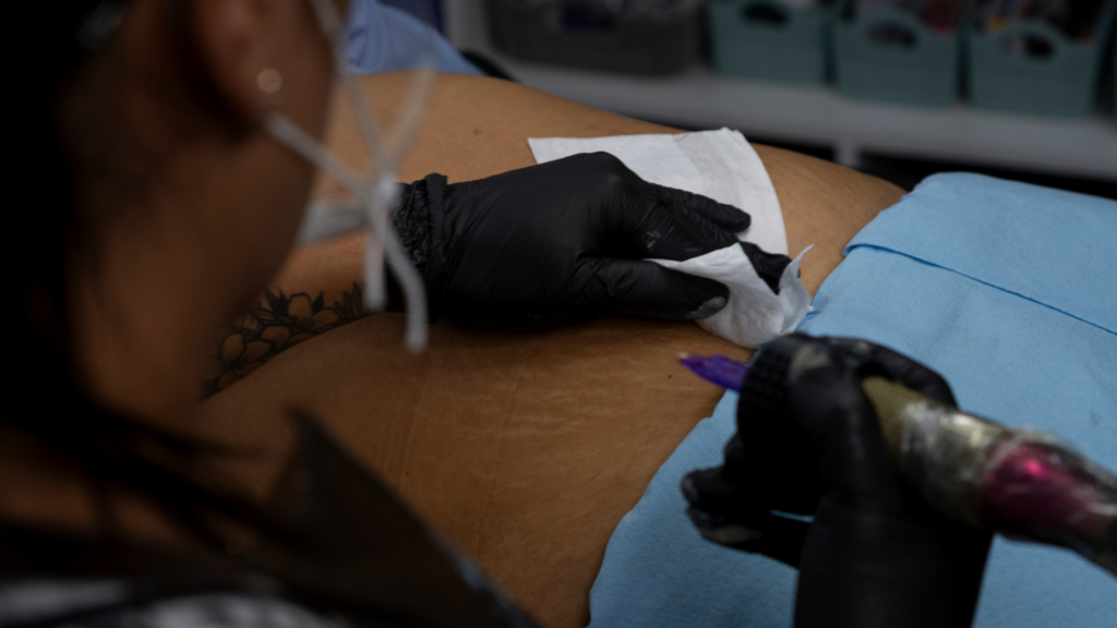 Close-up of a tattoo machine with a needle and ink cap on a clean surface