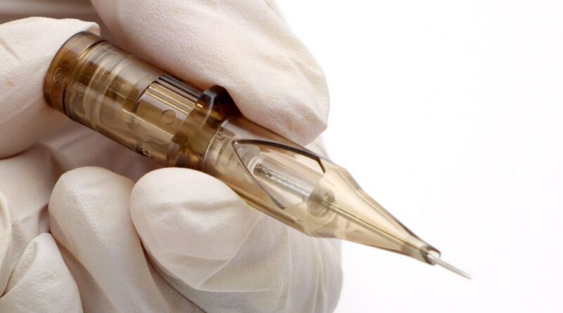 A tattoo artist holding a sealed package of cartridge needles.