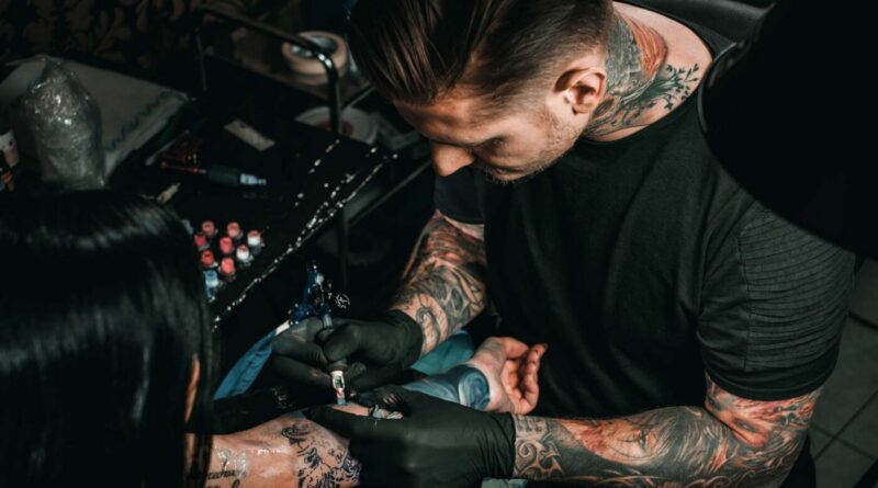 Tattoo artist tattooing a client at a convention booth