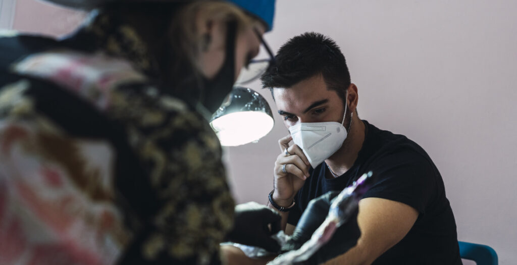 Tattoo artist wearing gloves and mask for hygiene