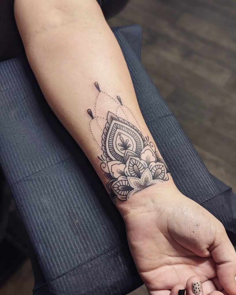 Close-up of a black ornamental tattoo on forearm showing intricate symmetrical patterns.