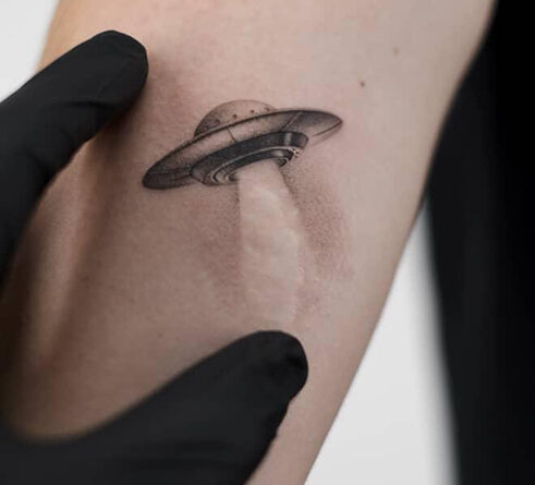 Tattoo artist using a magnifying lamp to apply fine details in a micro realism tattoo.