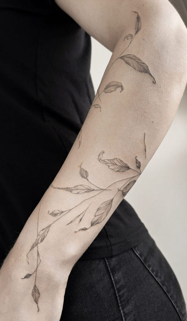 A fine line botanical tattoo featuring a single stem flower on the forearm.