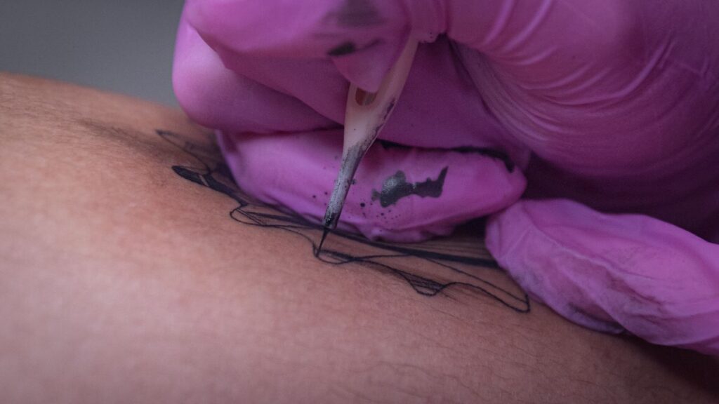 Tattoo artist consultation desk with neo-traditional design sketches and color swatches.