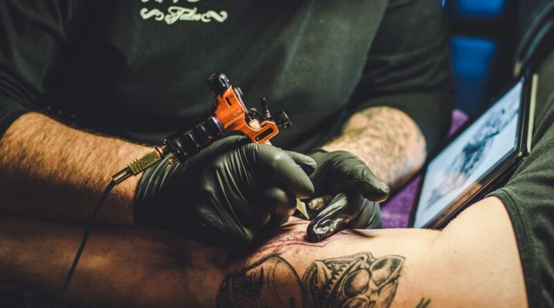 Tattoo artist carefully applying a transparent second skin bandage over fresh ink.