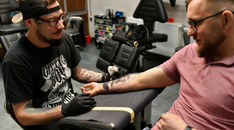 Tattoo artist's hand holding a needle cartridge, emphasizing the tip.