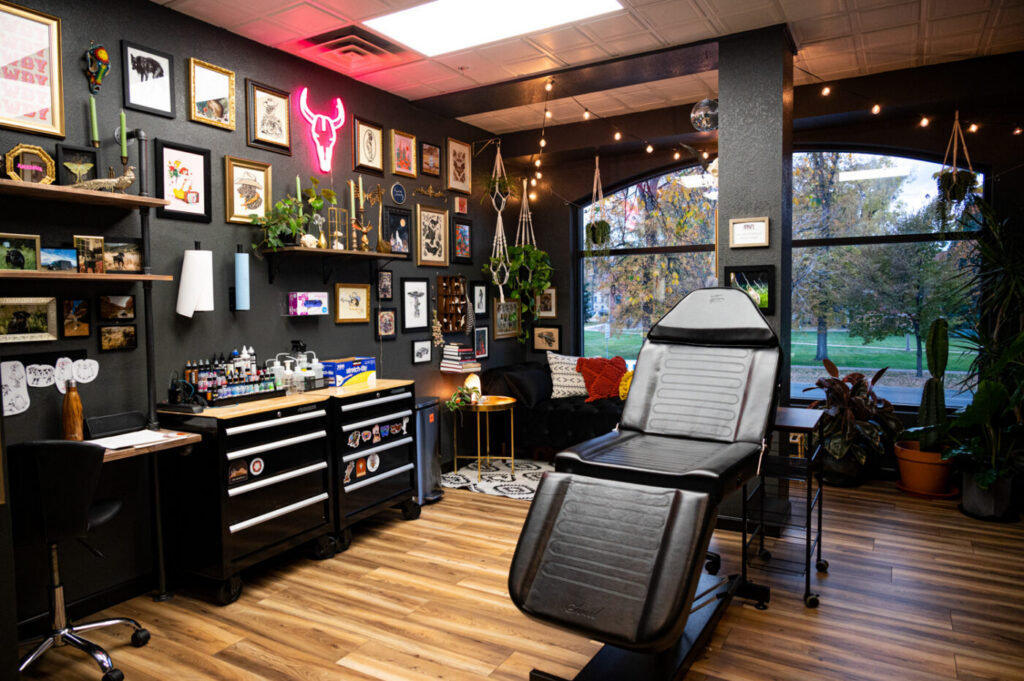 A person researching and comparing tattoo studios online, with a notebook and pen.