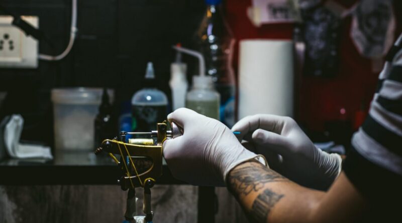 Tattoo artist preparing a sterile workstation with machine, needles, and ink cups for a session.