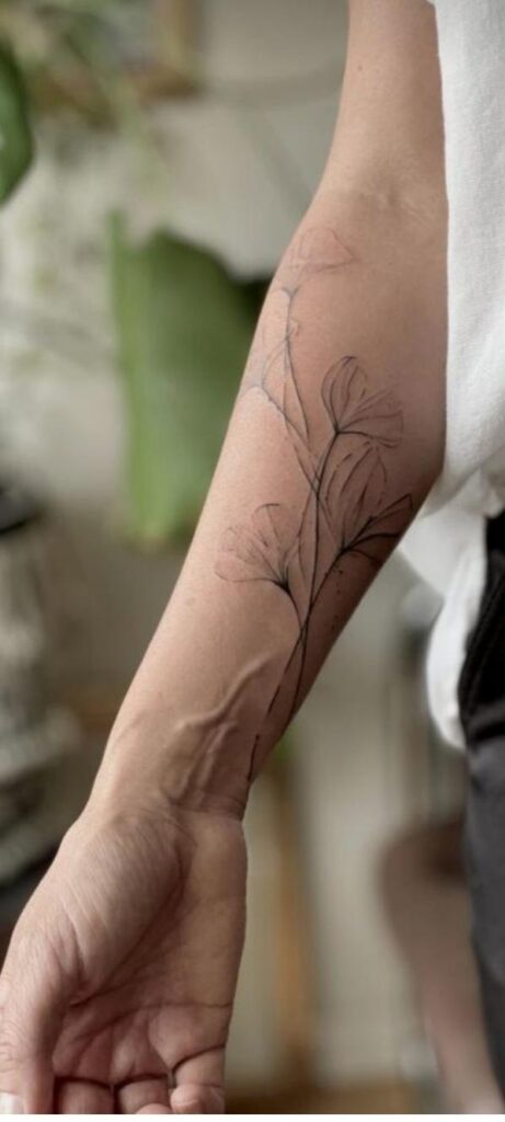 An aged fine line tattoo showing slight line spread and fading.