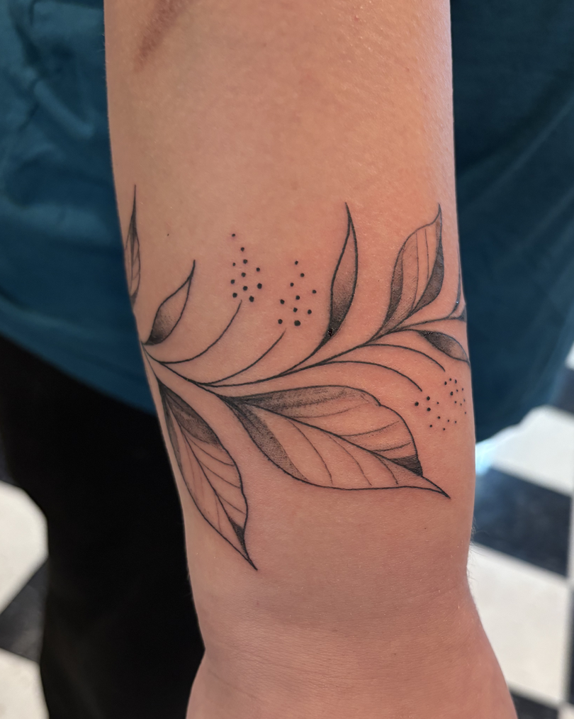 Delicate fern fronds tattooed with fine lines, showing natural stem curves.