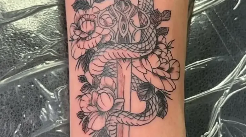 Tattoo artist applying a traditional bold-line tattoo in a clean studio.