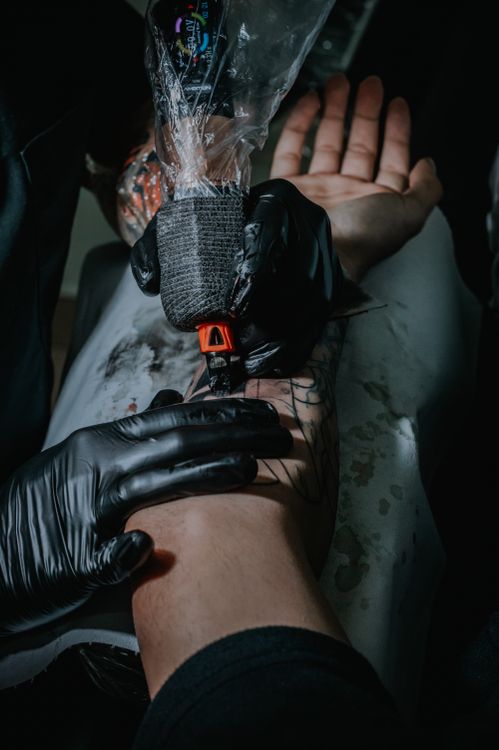 Tattoo artist placing a stencil on a client's arm before tattooing