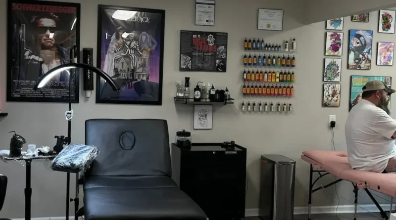 An artist places a stencil, the first step in a traditional tattoo.