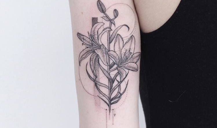 A tattoo artist sketching a black and grey design on paper during a consultation.