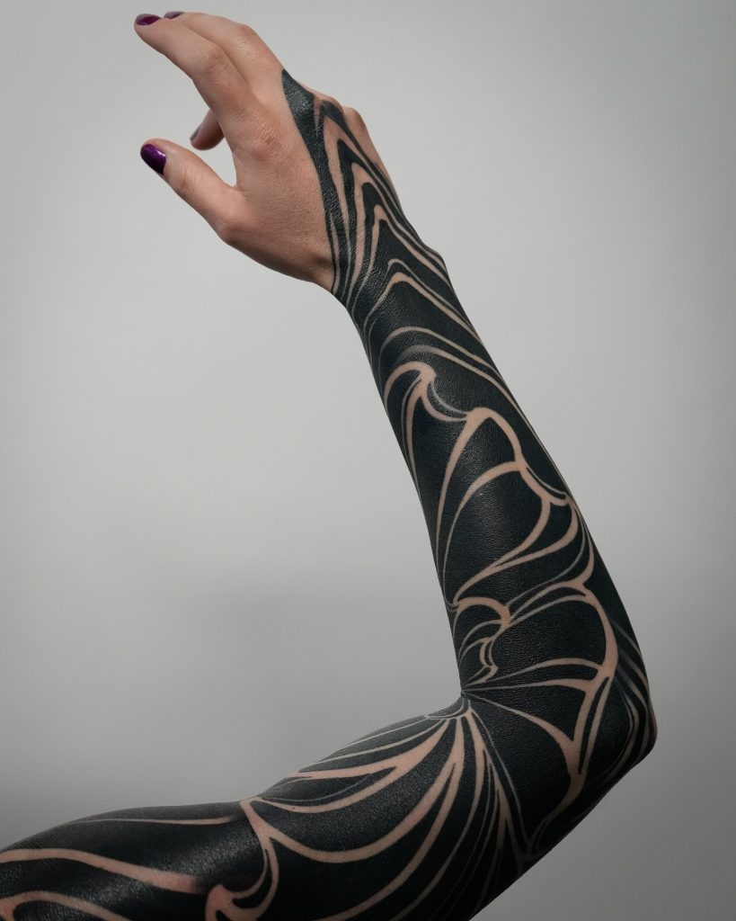Artist placing stencil for blackwork design with negative space