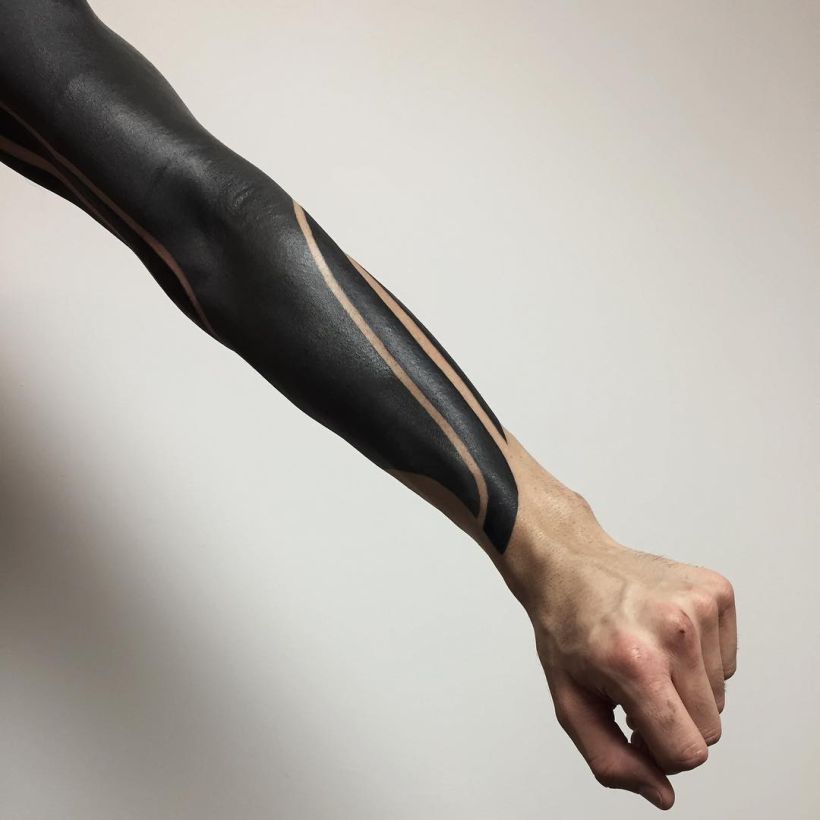 Blackwork tattoo flowing along shoulder and arm muscles