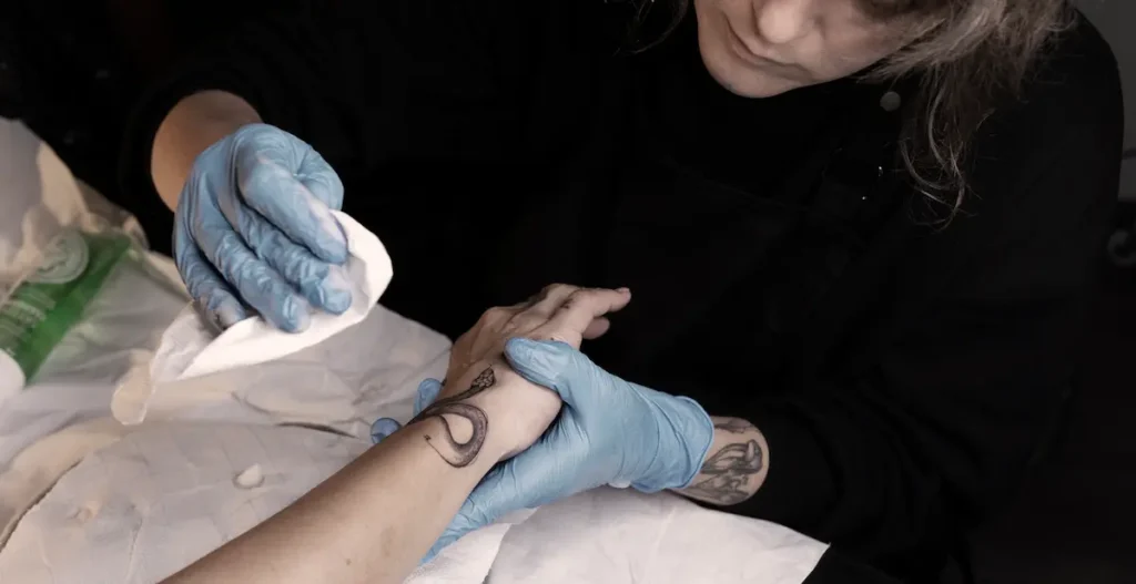 Applying aftercare film to a new fine line tattoo